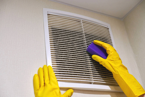 Manos en guantes de goma protectora limpiando la rejilla de ventilación de aire polvoriento de HVAC. Servicio de limpieza concepto. - Foto, imagen