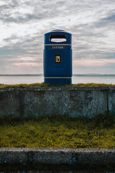 Изолированный мусорный бак на берегу моря Саутси в Портсмуте. Голубой мусорный бак с золотыми ободками. Зимний снимок сделан с видом на остров Уайт. - Фото, изображение
