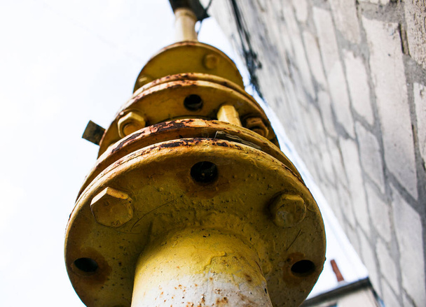Żółta rura gazowa z zamkniętym zaworem biegnie wzdłuż fasady budynku wielokondygnacyjnego. Dom przyłączony do gazu do użytku domowego. - Zdjęcie, obraz