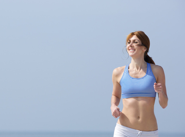 Smiling woman jogging outdoors - Photo, Image