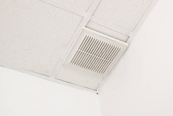 Parrilla de ventilación en un techo de baldosas blancas de cerca - Foto, Imagen