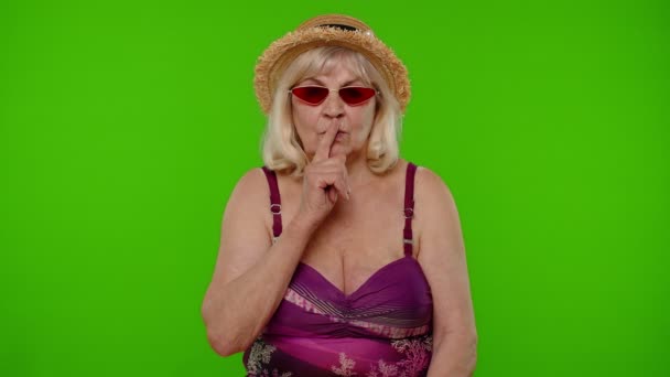 Turista anciana sosteniendo el dedo cerca de los labios para silencio signo, silencio, secreto, silencio en clave de croma - Imágenes, Vídeo