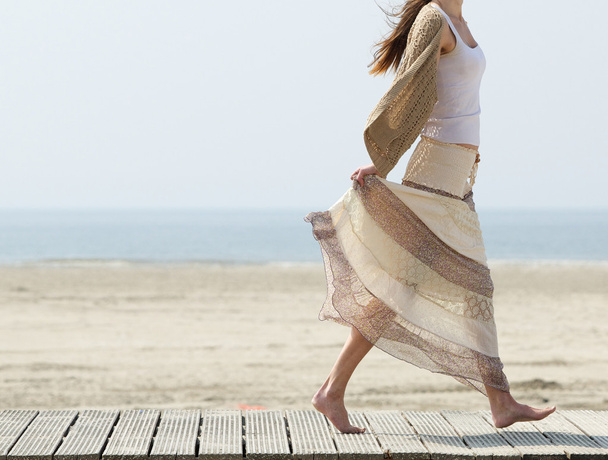 Женщина, гуляющая по пляжу босиком с платьем
 - Фото, изображение