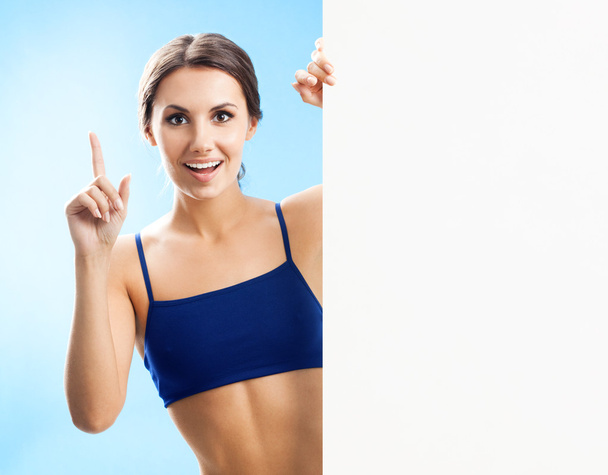 Woman in fitnesswear showing signboard, over blue - Φωτογραφία, εικόνα