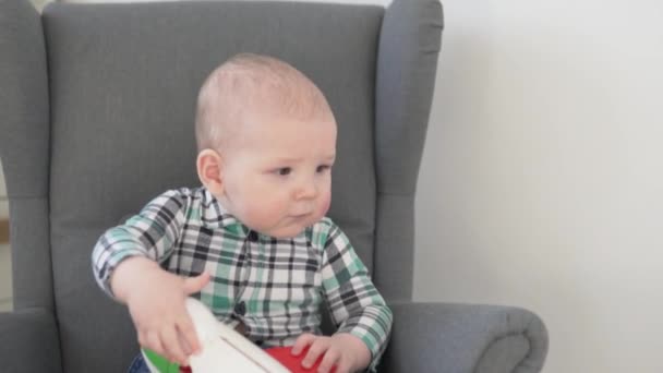 mignon petit enfant dans une chemise assis dans une chaise bébé. - Séquence, vidéo