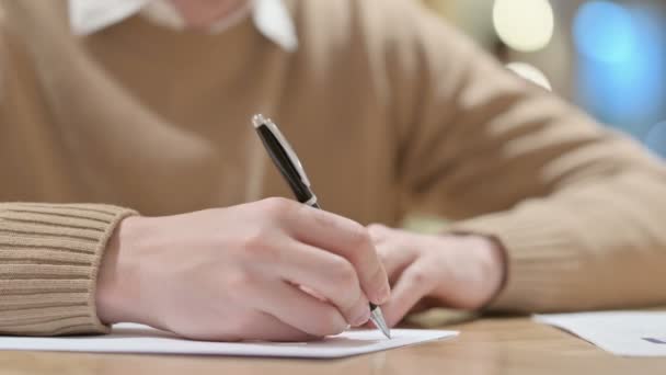 Close-up van de handen van de jonge man schrijven op papier  - Video