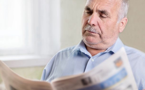 Homme caucasien supérieur lisant un journal à la maison
 - Photo, image