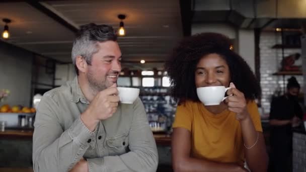 Ευτυχισμένο ζευγάρι κάνει αστεία και γελώντας πίνοντας ζεστό καφέ κάθεται στο μοντέρνο καφέ. - Πλάνα, βίντεο