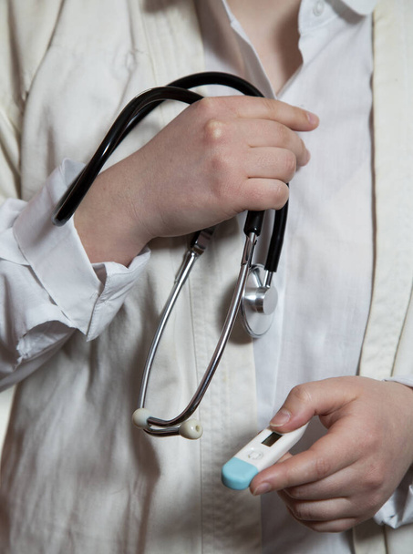 Een vrouwelijke arts heeft een stethoscoop en een thermometer. - Foto, afbeelding