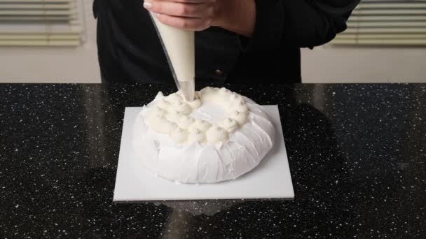 El chef de pastelería llena la torta con crema usando una bolsa de pastelería. Proceso de hacer pastel de Anna Pavlova. - Metraje, vídeo