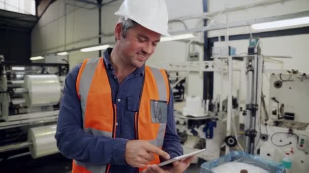 Männlicher Geschäftsmann blättert Checkliste auf digitalem Tablet glücklich lächelnd im Fabrikshop - Filmmaterial, Video