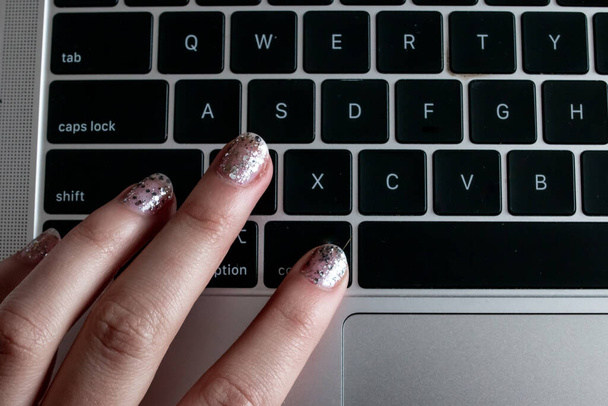 раскрашенные ногти женщины нажимают на кнопку команды на персональном компьютере во время работы на дому, февраль 2021.  - Фото, изображение