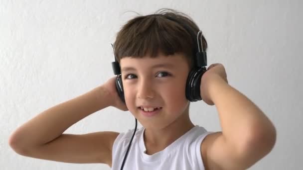 Young Kid está escuchando música con los auriculares - Imágenes, Vídeo