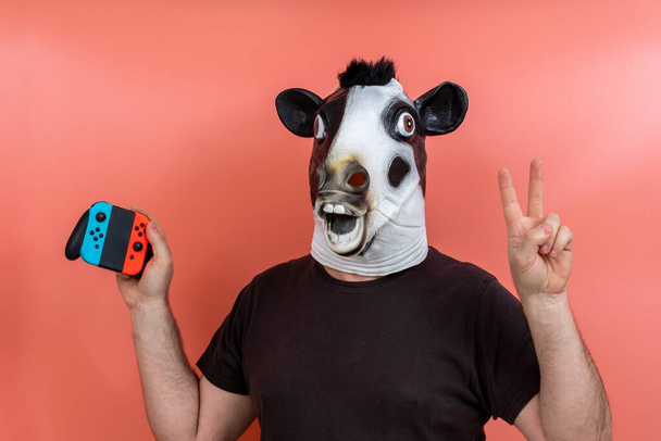 henkilö naamioitunut lehmä joystick juhlii voittoa videopeli vaaleanpunainen tausta - Valokuva, kuva
