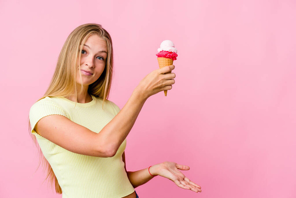 Mladý ruský žena jíst zmrzlinu izolované šokované a ohromený držení kopie prostor mezi rukama. - Fotografie, Obrázek