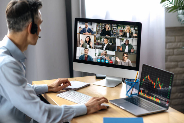 ビジネスミーティングオンライン。成功したビジネスマンは、職場に座っている間にコンピュータを使用してビデオ会議で多人種ビジネスパートナーと交渉しています。 - 写真・画像
