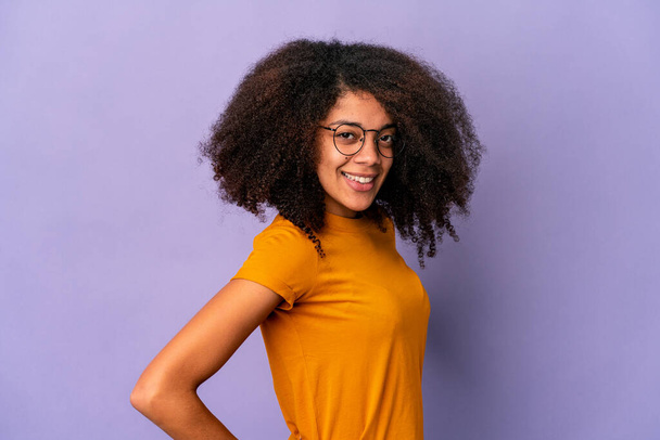 Young african american curly woman isolated on purple background confident keeping hands on hips. - Zdjęcie, obraz