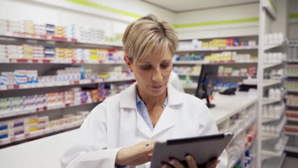 Női menedzser görgetés keresztül digitális tabletta válogatás e-maileket főnök áll a gyógyszertárban  - Felvétel, videó