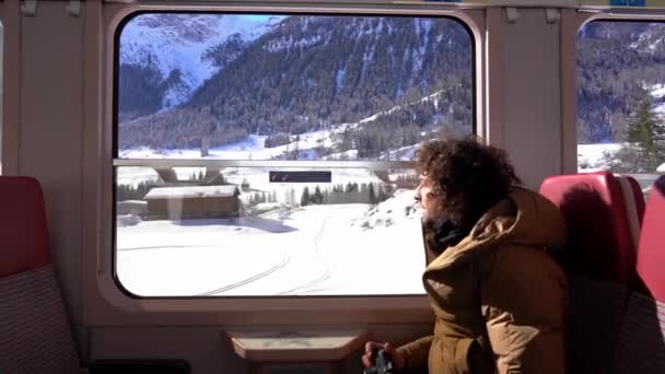 Мандрівний блогер - каукасіан, якому 40 років, фотографує і фотографує з вікна поїзда під час подорожі гірським ландшафтом - Берніна Експрес, світ спадщини Унеско.  - Кадри, відео