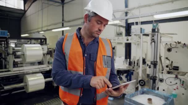 mężczyzna biznes człowiek przewijanie przez e-maile na cyfrowy tablet czat z menedżer stojący w fabryce  - Materiał filmowy, wideo