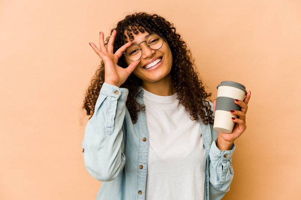 jovem afro americano africano mulher segurando um takeaway café animado mantendo ok gesto no olho. - Foto, Imagem