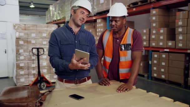 colegas de raza mixta discutir ideas de negocio mirando tableta de pie en el almacén - Metraje, vídeo