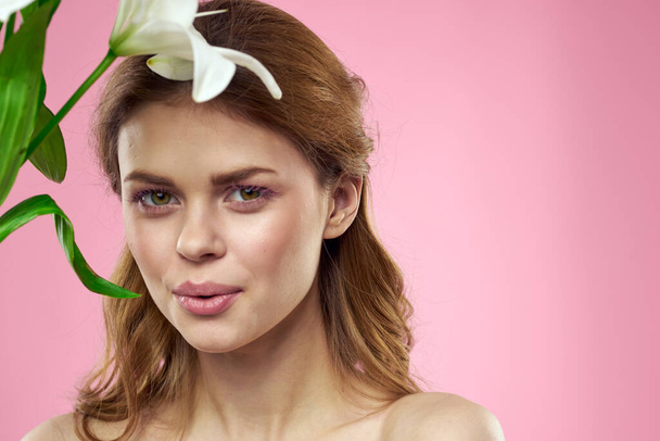 ピンクの背景のメイクの肖像モデルの花を持つ美しい女性 - 写真・画像