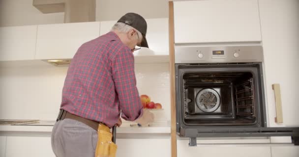 Electricista senior fijando las luces en el horno - Metraje, vídeo