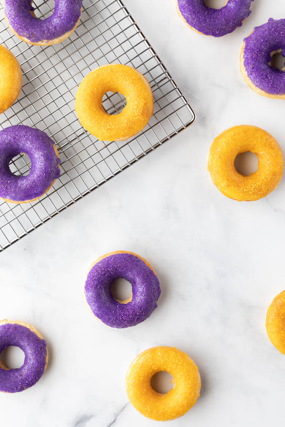Top down view of donuts on a white marble background with some donuts on a cooling rack. - Valokuva, kuva