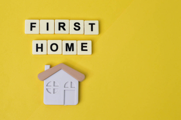 Toy house and square letters with text FIRST HOME. - 写真・画像