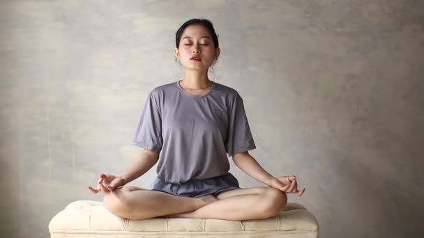 Azjatka ćwiczy jogę medytując w domu, pozycję lotosu. Brak stresu, uważności, koncepcja równowagi wewnętrznej - Materiał filmowy, wideo