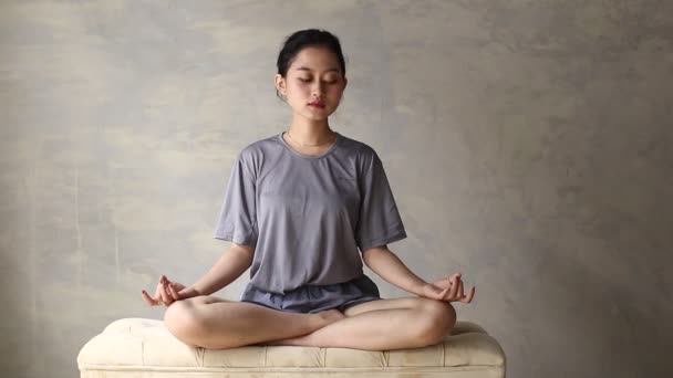 Aasialainen nainen harrastaa joogaa meditointia sisätiloissa, lootusasentoa. Ei stressiä, tietoisuus, sisäinen tasapaino käsite - Materiaali, video