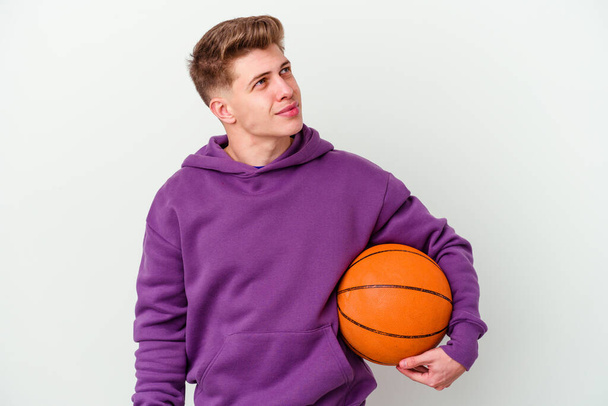 Jeune homme caucasien jouant au basket-ball fond isolé rêvant d'atteindre des objectifs et des buts - Photo, image