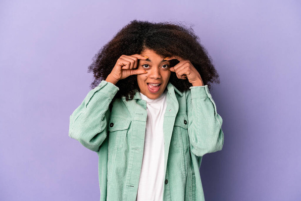 Mladý africký americký kudrnatý žena izolovaný na fialové pozadí udržet oči otevřené najít příležitost k úspěchu. - Fotografie, Obrázek