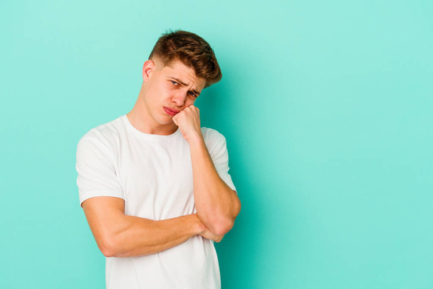 Young caucasian man isolated on blue background who feels sad and pensive, looking at copy space. - Foto, Imagen