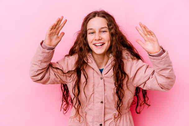 Pequena menina caucasiana isolado no fundo rosa recebendo uma agradável surpresa, animado e levantando as mãos. - Foto, Imagem