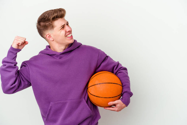 Молодий білий чоловік грає в баскетбол ізольований фон, піднімаючи кулак після перемоги, концепція переможця
. - Фото, зображення