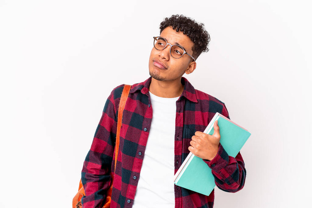 Junger afrikanisch-amerikanischer Student lockiger Mann, der verwirrt Bücher hält, fühlt sich zweifelhaft und unsicher. - Foto, Bild
