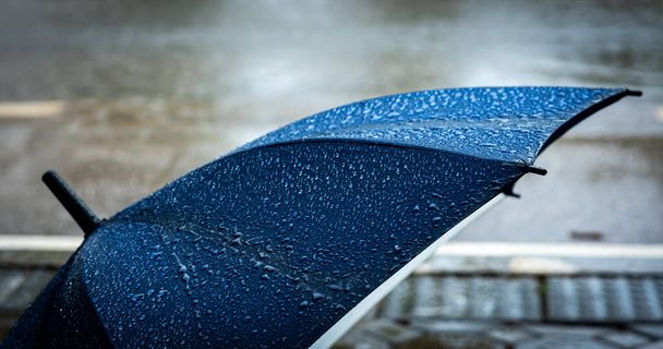 Yolun yakınındaki yağmurda yere konmuş mavi şemsiyenin klasik ton görüntüsü. - Fotoğraf, Görsel