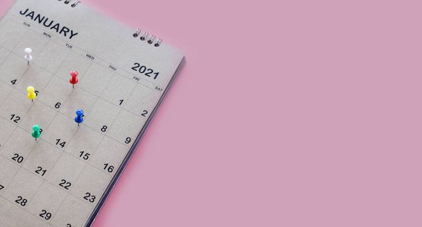 Kalender en afspraak planner met een pin op een roze achtergrond. - Foto, afbeelding