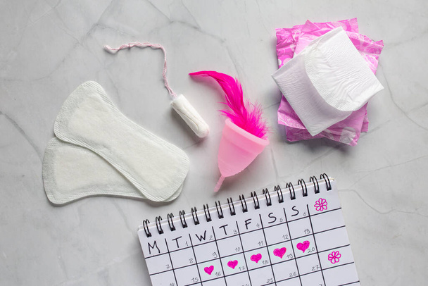 Menstruációs naptár pamut tamponokkal. Női higiéniai védelem. Női kritikus napok. Női higiéniai eszközök, női higiéniai párnák, csésze, menstruáció - Fotó, kép