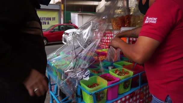 Homme à un stand de bonbons servant des bonbons dans un petit sac en plastique - Séquence, vidéo