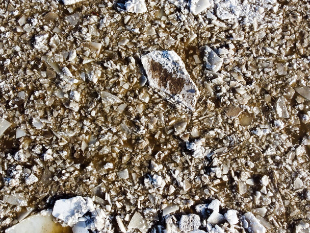 Abstracte textuur van gebroken wit ijs en donker water in de winter. De lente komt eraan. Zicht vanuit de lucht op het bevroren oppervlak. - Foto, afbeelding