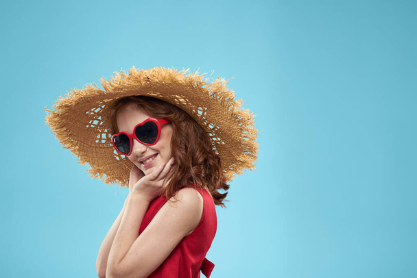 Chica en una playa Sombrero de paja en gafas de sol pelo rizado divertido fondo azul - Foto, imagen