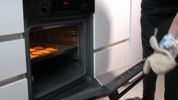 mujer irreconocible saca una galleta preparada del horno - Metraje, vídeo