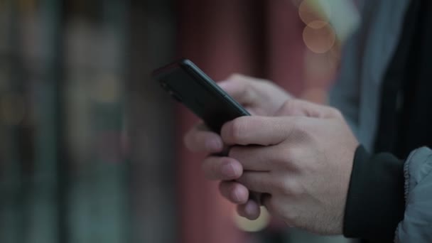 Close-up van een smartphone in de handen van een jongeman.  - Video