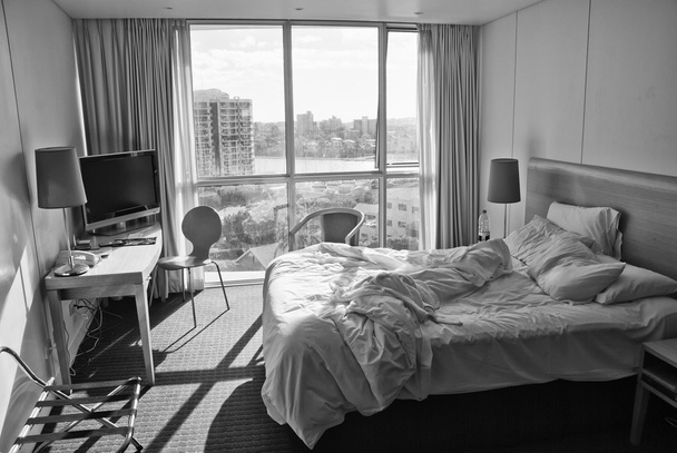 Quarto de Hotel com Cama Desfeita e Vista Cidade, Austrália
 - Foto, Imagem