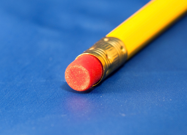Red rubber on the yellow pencil against the blue background - Photo, Image