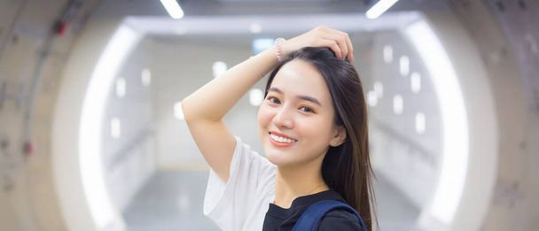 Une belle femme asiatique portant une chemise noire se tenait souriante alors qu'elle entrait dans un tunnel de métro. - Photo, image