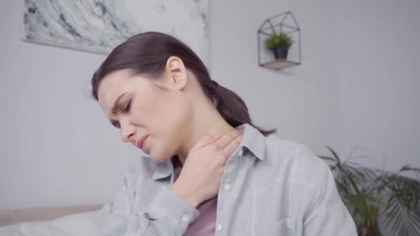 brunetka młoda kobieta dotyka szyi podczas gdy cierpi z powodu bólu - Materiał filmowy, wideo